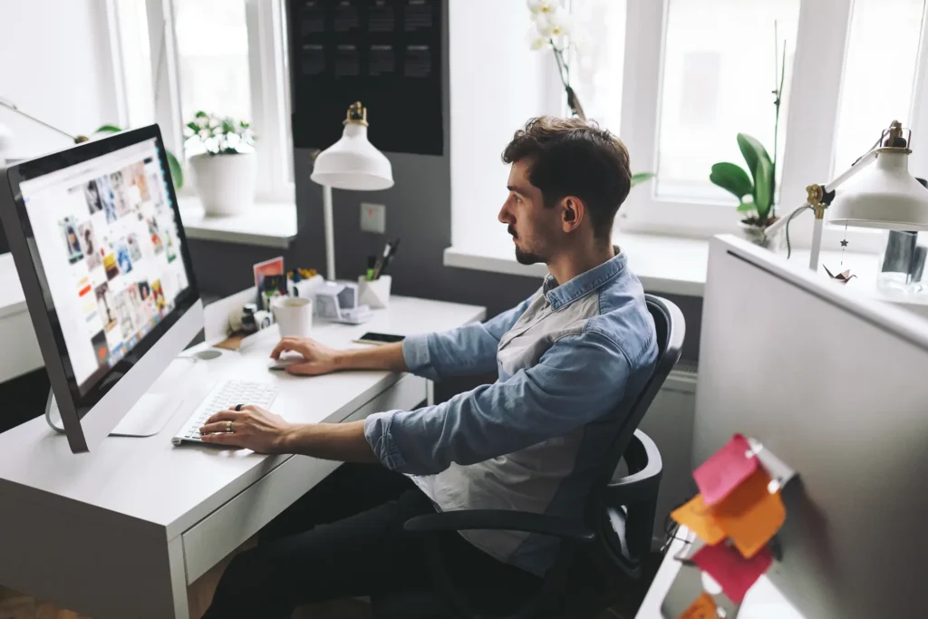 person sitting at his work table working on website design on his computer